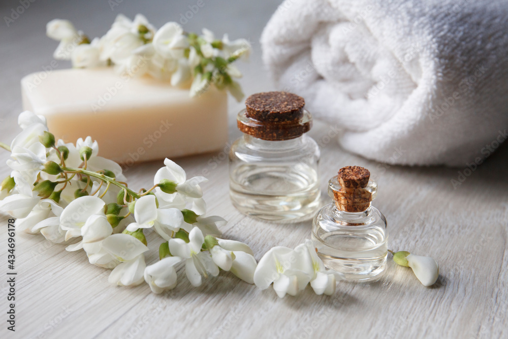 Robinia (false acacia) essential oil (remedy, extract) bottle with fresh acacia flowers, soap, showel on wooden background, selective focus Robinia (false acacia) essential oil (remedy, extract) bottle with fresh acacia flowers, soap, showel on wooden background, selective focus