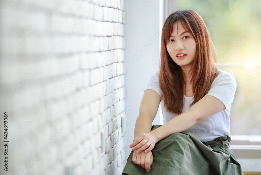 Serene woman sitting against window at home Serene woman sitting against window at home