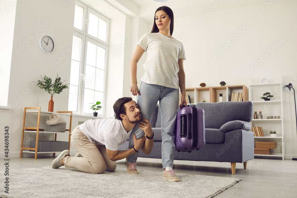 Young couple breaking up. Woman with packed bag leaving home. Funny clingy  traitor husband on floor holding wife's leg imploring her to give second  chance. Relationship breakup and divorce concept Stock Photo |