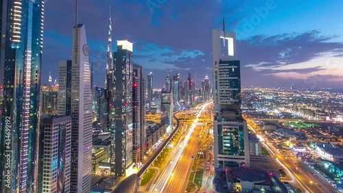 Wallpaper Mural Dubai downtown architecture day to night transition timelapse. Top aerial view over Sheikh Zayed road with illuminated skyscrapers and traffic. Beautiful cloudy sky Torontodigital.ca