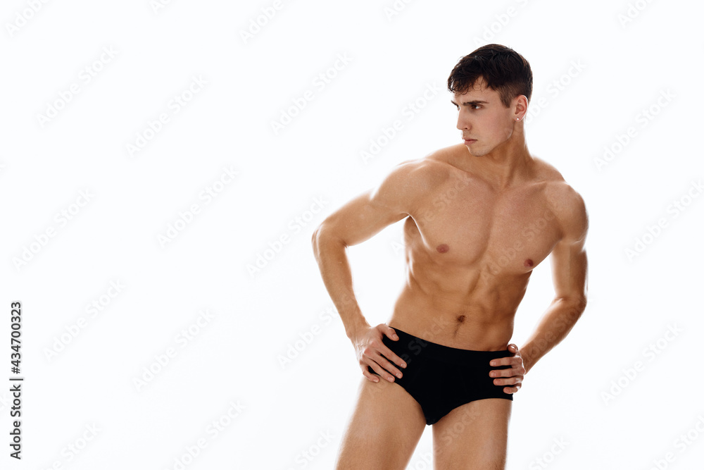 handsome man athlete with a pumped-up body in dark shorts on a light background handsome man athlete with a pumped-up body in dark shorts on a light background