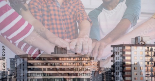 Composition of ffice colleagues hand stacking over cityscape photo