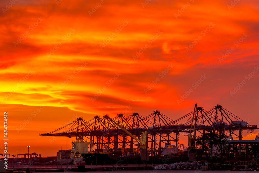Sky burst with silhouette Crane bridge during sunset at Container terminal seaport