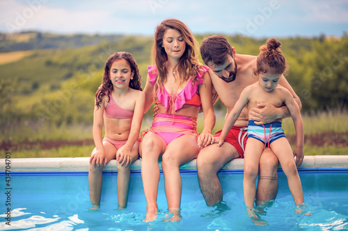 Happy family sitting by the swimming pool.
