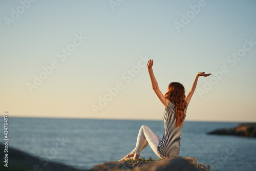 woman on the bank near the river with raised up arms back view striped t-shirt pants