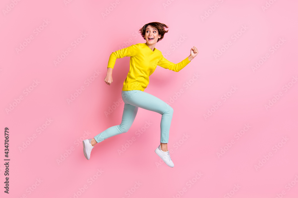Full length body size photo of woman jumping high running fast looking back isolated on pastel pink color background