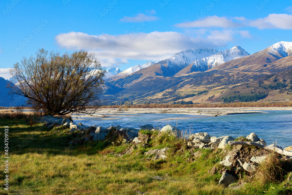 The Dart River in the Otago region of New Zealand's South Island, with the snow-capped mountains of the Southern Alps in the background