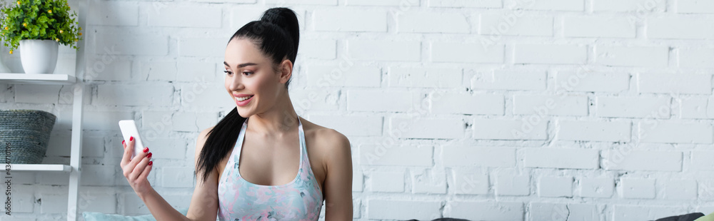 smiling woman in sportswear using smartphone at home, banner smiling woman in sportswear using smartphone at home, banner