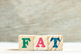 Alphabet letter block in word FAT (Obesity or abbreviation of factory acceptance test, file allocation table) on wood background