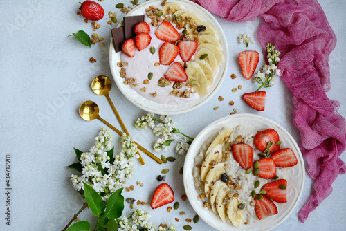 Top view of two plates with muesli, porridge, yogurt and strawberries on a lilac background. Healthy and nutritious breakfast