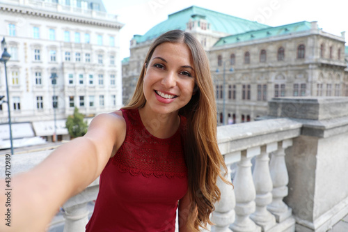 Tourist girl takes self portrait in Vienna with famous historic palaces State Opera and Hotel Sacher, Austria, Europe photo