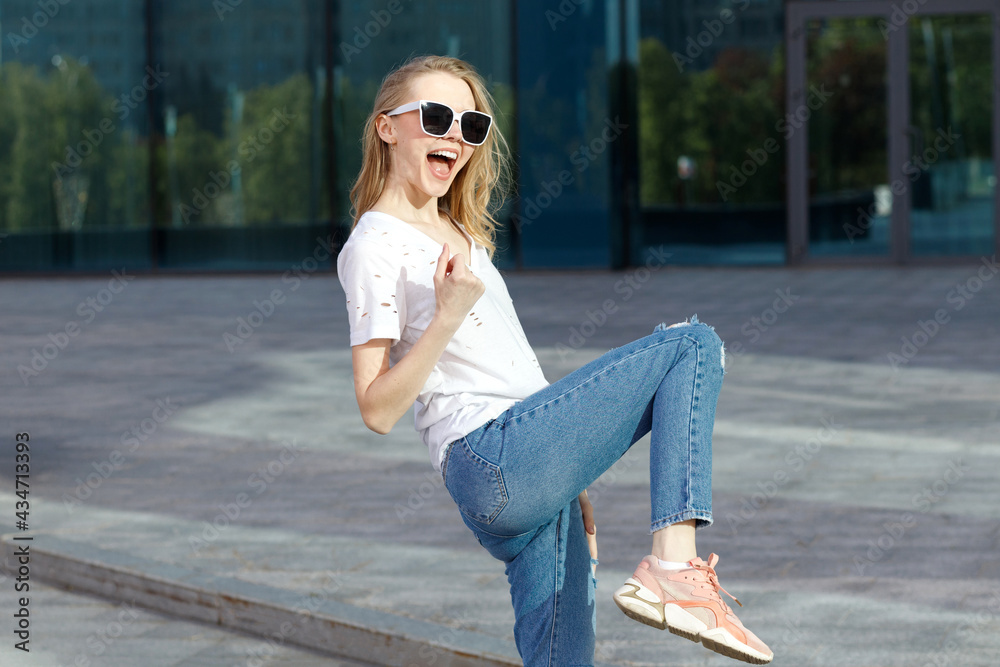 Emotional attractive blonde in glasses and white T-shirt shows emotions on a blue background in the summer Emotional attractive blonde in glasses and white T-shirt shows emotions on a blue background in the summer
