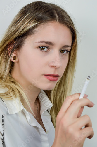Portrait of a beautiful young blonde woman who is smoking a cigarette and is looking at camera