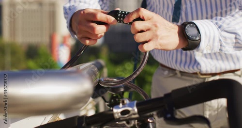 Mid section of asian man locking his bicycle at corporate park