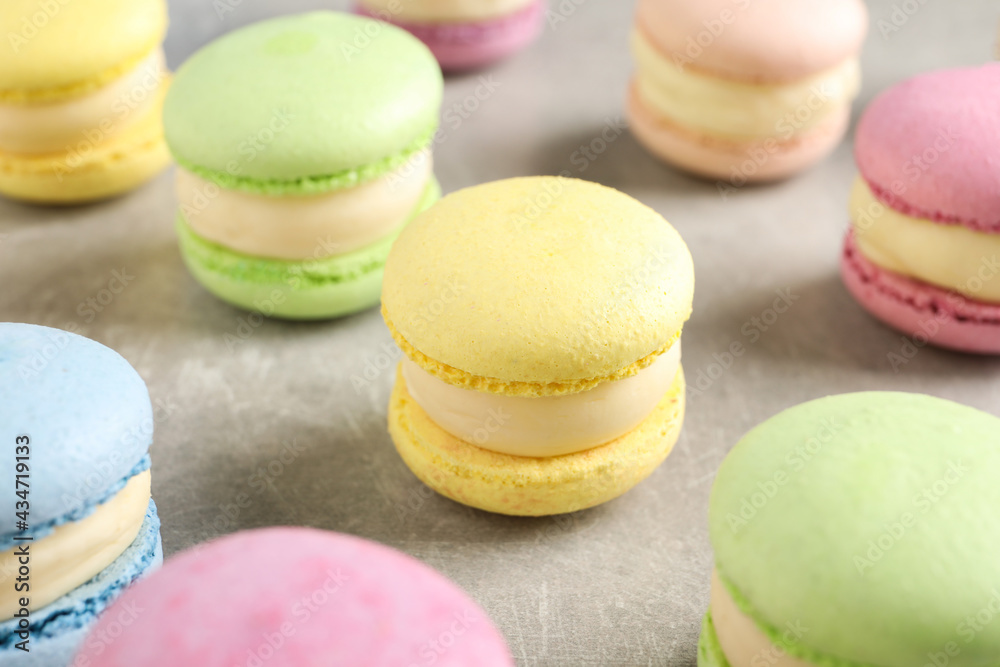Many delicious colorful macarons on grey table, closeup