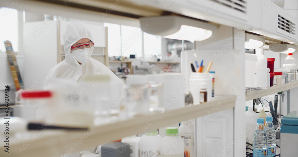 Scientist wearing protective overall, goggles and mask working in biochemical laboratory Scientist wearing protective overall, goggles and mask working in biochemical laboratory