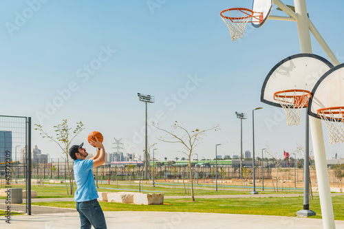 Side view of a young boy playing basketball in a sports park. © Marcela Ruty Romero