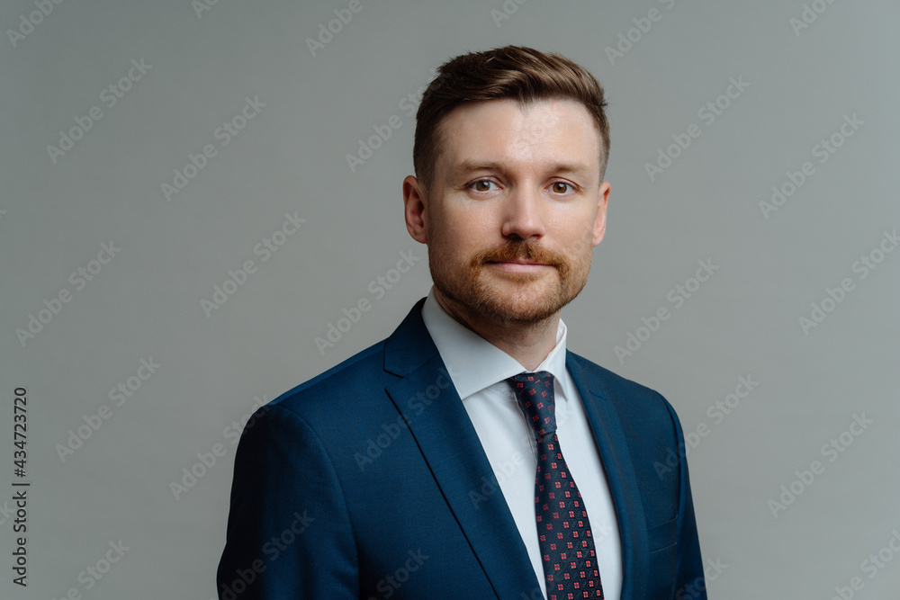 Handsome unshaven man in suit posing against grey background Handsome unshaven man in suit posing against grey background