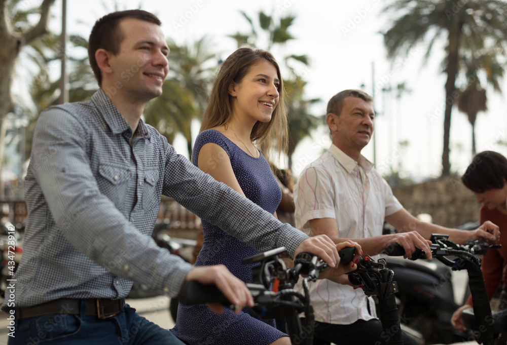 friends of tourists of different generations enjoy a ride on electric scooters