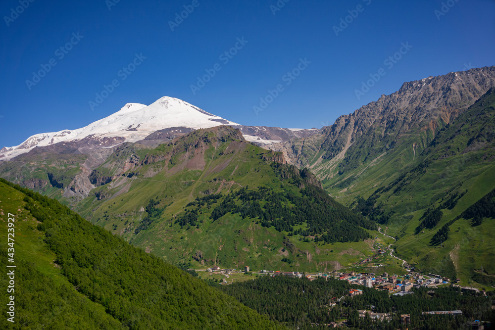 Elbrus is the highest mountain in Europe. Elbrus Volkano is a big volcano located in the south-east Caucasus mountain range in Kabardino-Balkaria, Russia. Viem from Cheget mount. July. Panoramic view