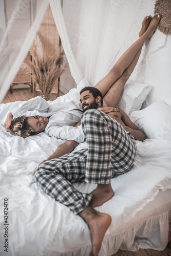 Happy man and woman in home clothes on bed © zinkevych