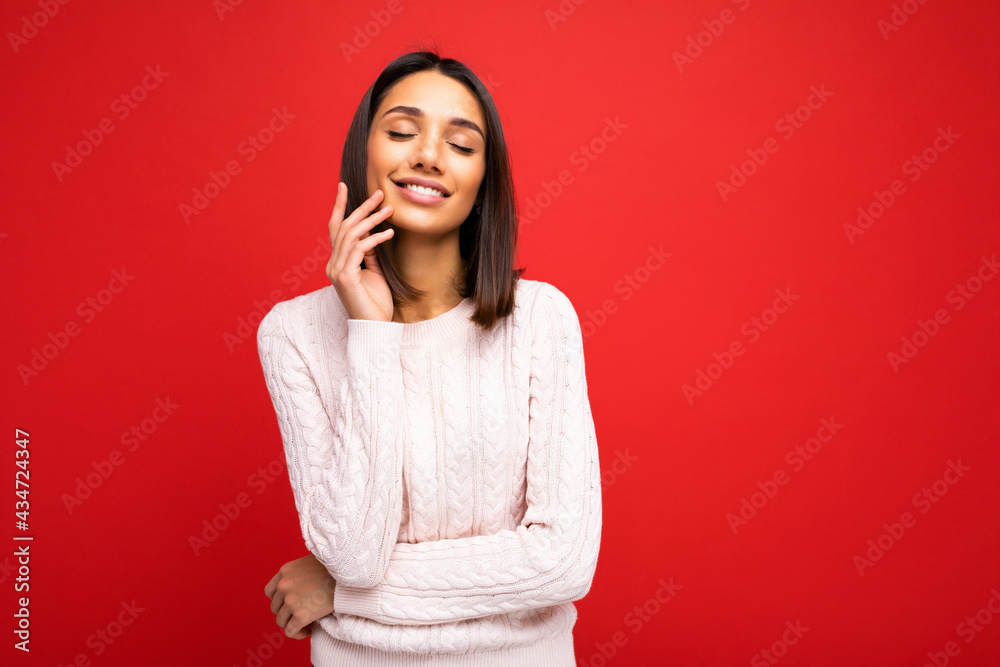 Portrait of positive cheerful cute smiling young brunette woman in casual sweater isolated on red background with copy space Portrait of positive cheerful cute smiling young brunette woman in casual sweater isolated on red background with copy space