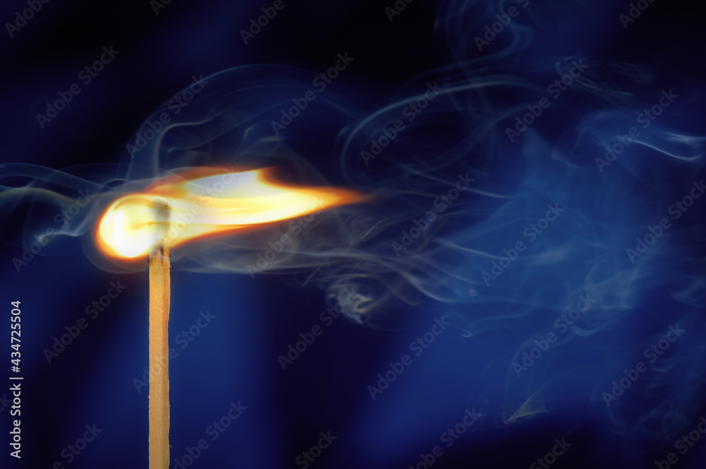 Burning match with flame and smoke on deep blue background Burning match with flame and smoke on deep blue background