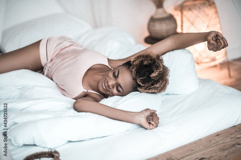 Cheerful woman in pajamas stretching on bed Cheerful woman in pajamas stretching on bed