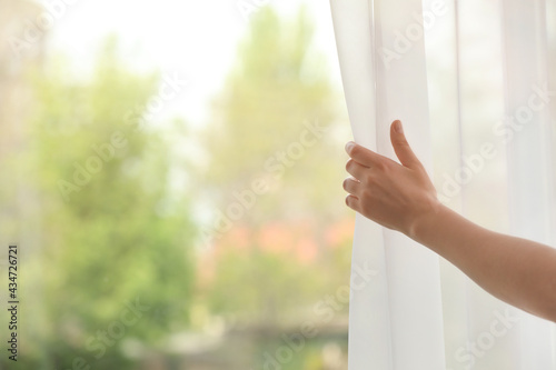 Woman opening curtain indoors, closeup. Space for text Free Download Woman opening curtain indoors, closeup. Space for text - GFXLoad