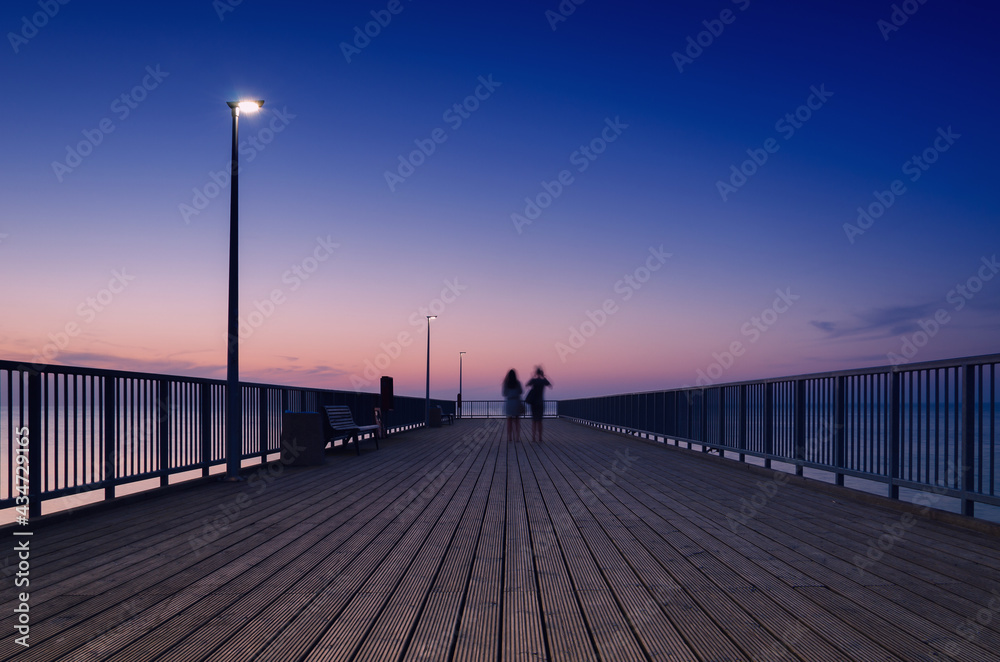 PIER ON THE SEA COAST - Womens walk at a quiet sunset 