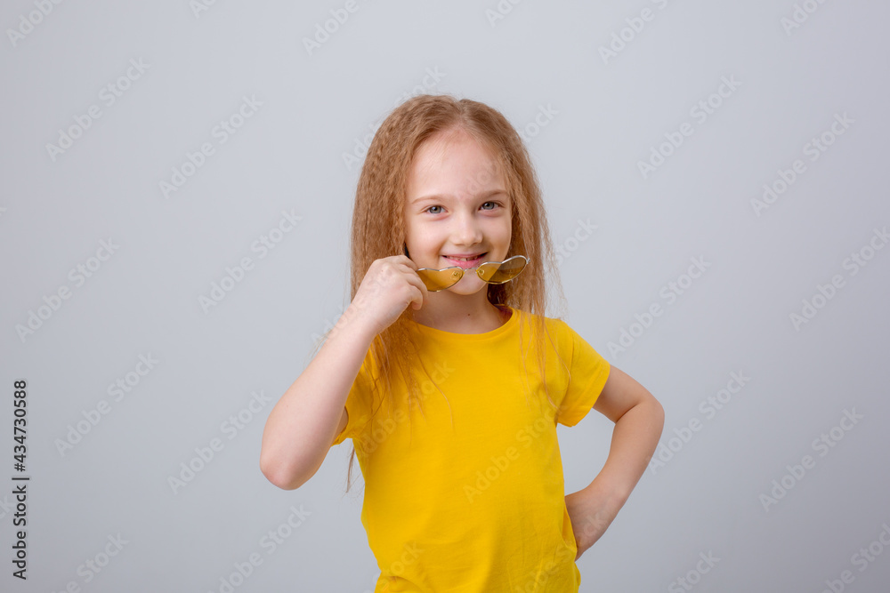a little girl in sunglasses smiles on a white background a little girl in sunglasses smiles on a white background