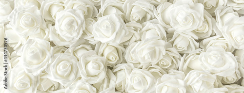 banner with background of many fake white roses. Top view.
