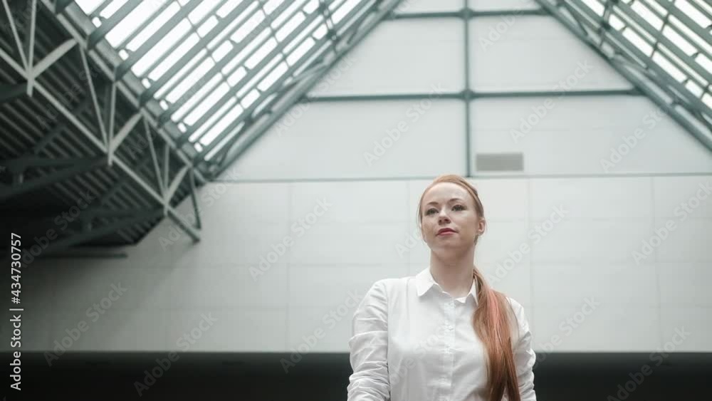 Attractive young Caucasian businesswoman in formal attire walks through business center. A successful financial manager works in an office in a large corporation. A businesswoman walks in the hallway Attractive young Caucasian businesswoman in formal attire walks through business center. A successful financial manager works in an office in a large corporation. A businesswoman walks in the hallway