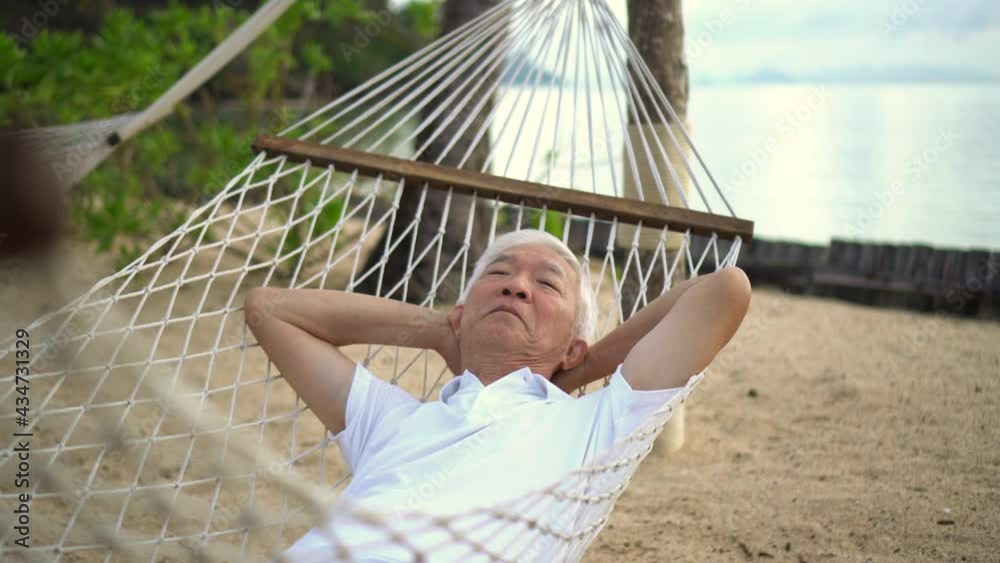 Asian senior elder man relax at beach resort hammock vacation retirement