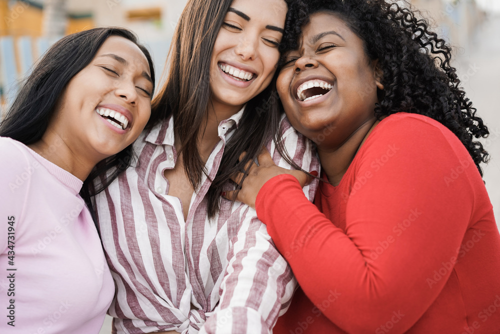 Obraz premium Happy hispanic women enjoy time together outdoor around city - Focus on black girl face
