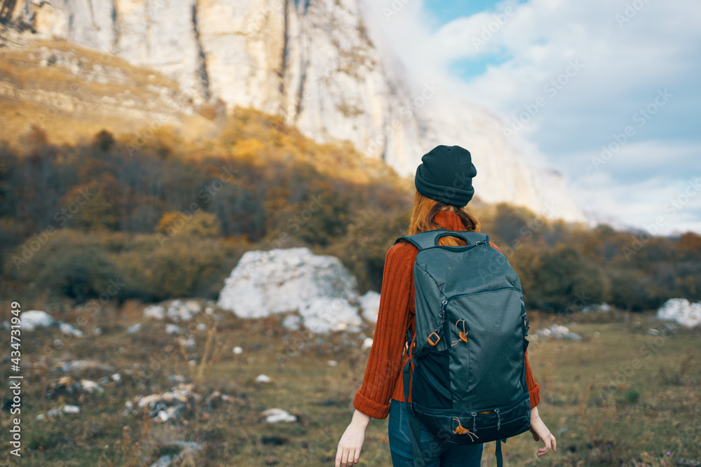 woman with a backpack walks on nature in the mountains in autumn blue sky rocks landscape woman with a backpack walks on nature in the mountains in autumn blue sky rocks landscape