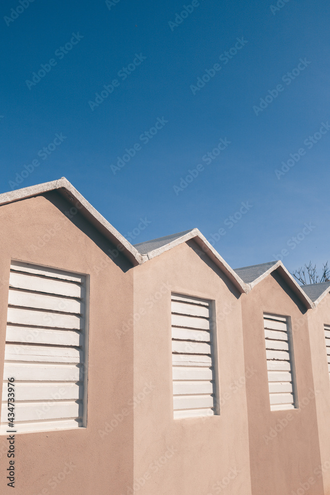 Close up shot of the typical beach huts and cabins in a beach in the Riviera Romagnola area of italy. Warm pastel colors in cotrast with a blue sky. Vintage summer mood and atmosphere. Close up shot of the typical beach huts and cabins in a beach in the Riviera Romagnola area of italy. Warm pastel colors in cotrast with a blue sky. Vintage summer mood and atmosphere.