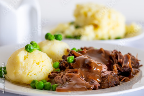 beef meat with gravy, mashed potatoes with green peas