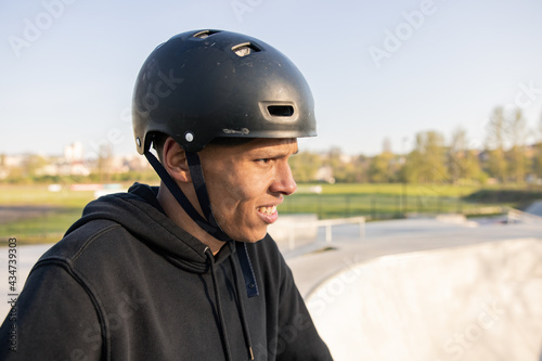 A cyclist stands on a ramp in a park on a spring afternoon with a helmet on his head and looks forward at the ramp wondering if he can pull off a new trick © ABCreative