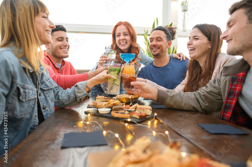 Multiracial friends drinking coloured cocktail at bar of restaurant - Friendship concept with young people having fun together toasting drinks on happy hour at pub