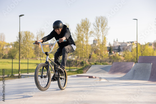 A young boy mastered riding a low trick bike,bmx, I try to lift the front wheel, he is fascinated, smiles, keeps his feet on the pedals lifting himself up