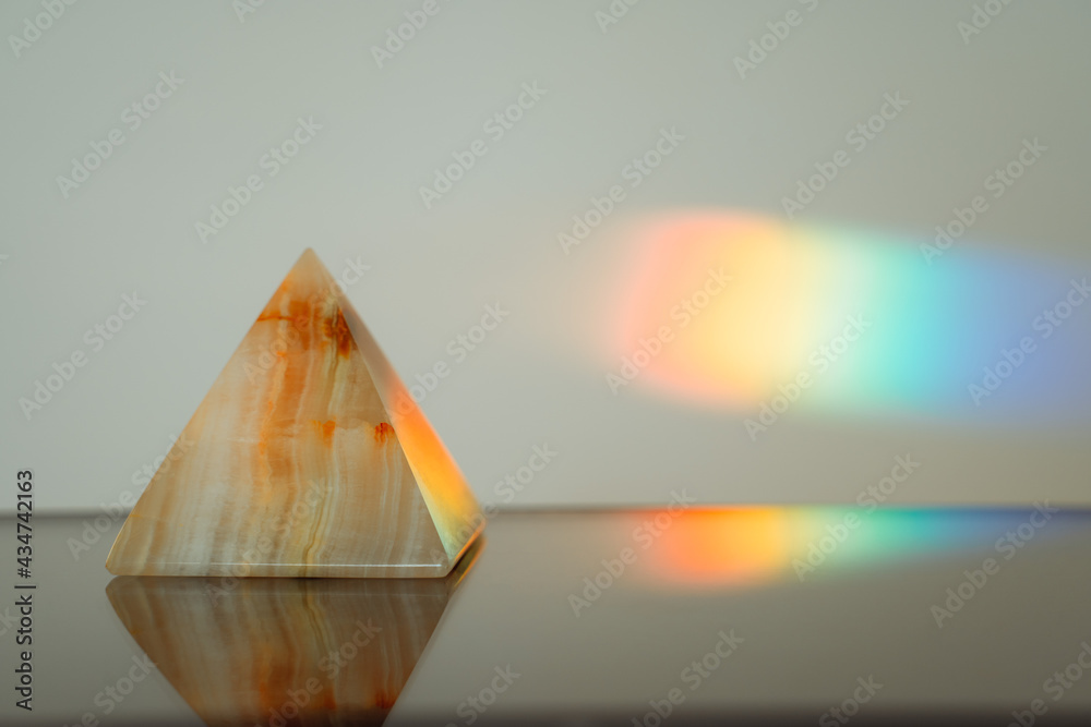 Agate pyramid with a rainbow streak background
