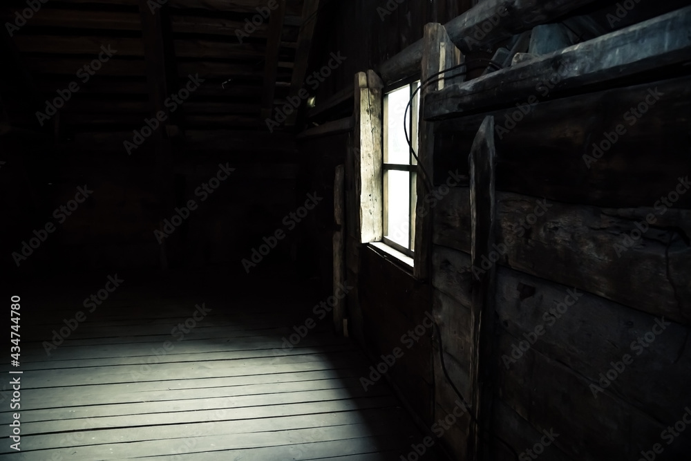 Horror background causing fear. Scary mystical mysterious dark attic room in an abandoned wooden old empty house with a strange ghostly light on the floor from the window