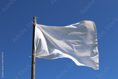 The white flag against the blue sky. Surrender concept.