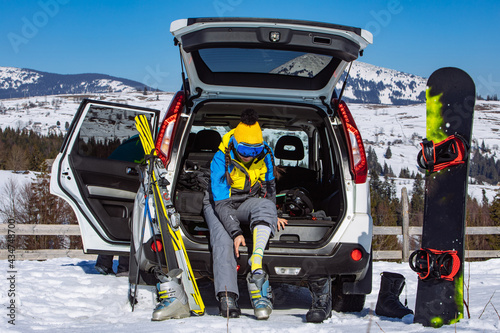 man and woman dressing into ski equipment near suv car