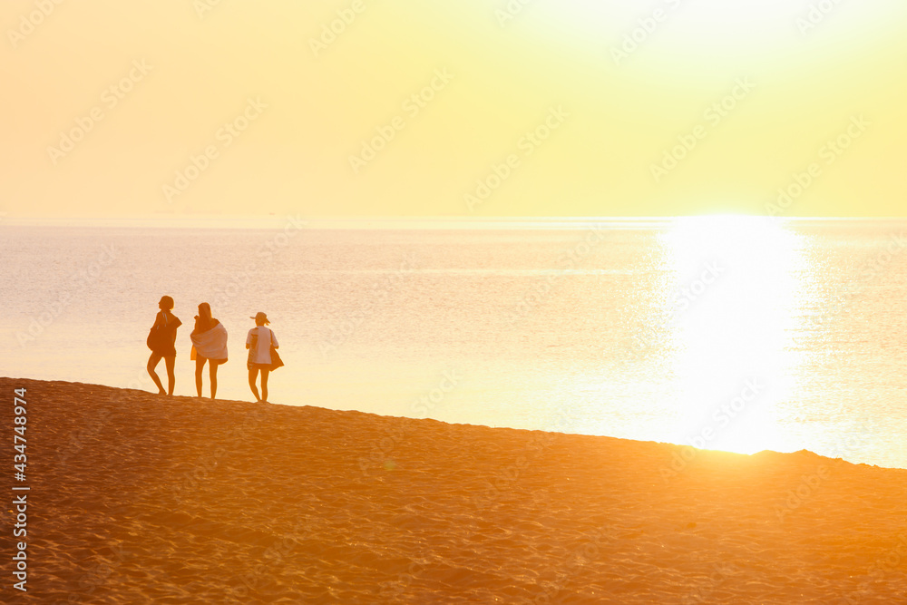 group of friends walking by sandy beach on sunset group of friends walking by sandy beach on sunset