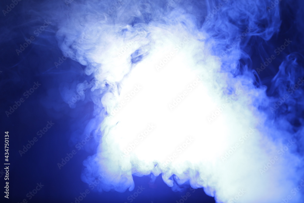 Magic artificial smoke in blue light on black background