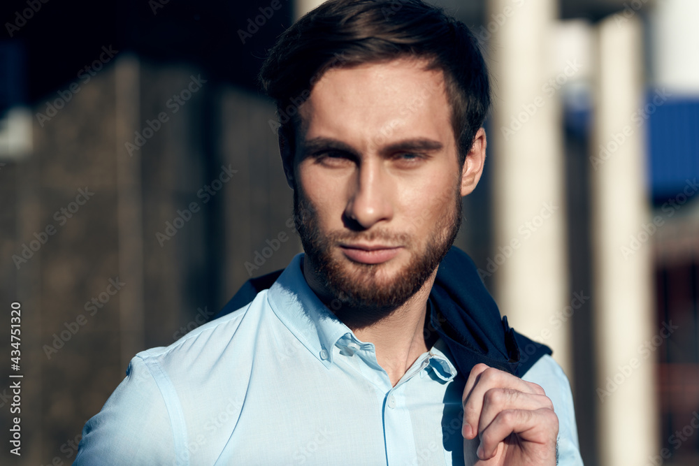 man in blue shirt with jacket on shoulder on street near building man in blue shirt with jacket on shoulder on street near building