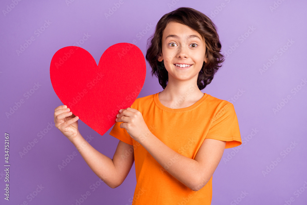 Portrait of attractive cheerful boy holding in hands big paper heart isolated over violet purple color background Portrait of attractive cheerful boy holding in hands big paper heart isolated over violet purple color background