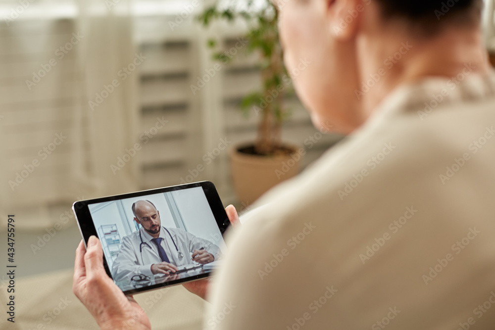 Telemedicine concept. Old woman with tablet during an online consultation with her doctor in her living room